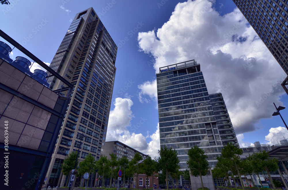 Amsterdam, Holland, August 2019. Several modern skyscrapers are located in the modern suburbs of the city. With extensive use of glass and steel they have facades that reflect the clouds in the sky.