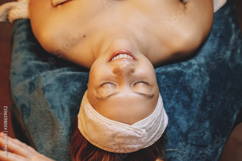 Top view portrait of a beautiful young woman leaning on a spa bed with eyes closed relaxing while doing skin care routine in a wellness spa salon. photo