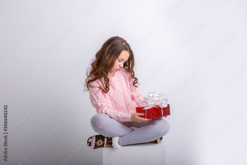 a little girl with a gift in her hands on an isolated white background shows emotion interest a little girl with a gift in her hands on an isolated white background shows emotion interest