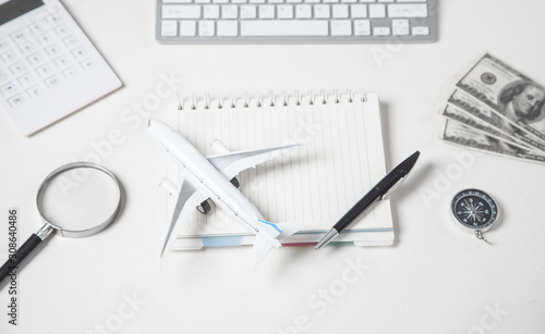 Airplane, money, keyboard, calculator on the white desk.