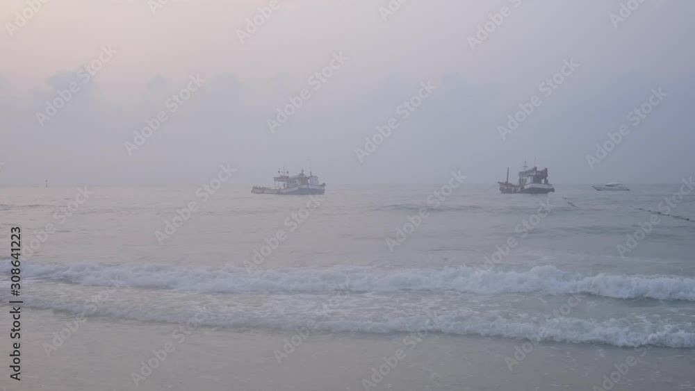 The sea is approaching the beach and a fishing boat floats in the sea. The sea is approaching the beach and a fishing boat floats in the sea.
