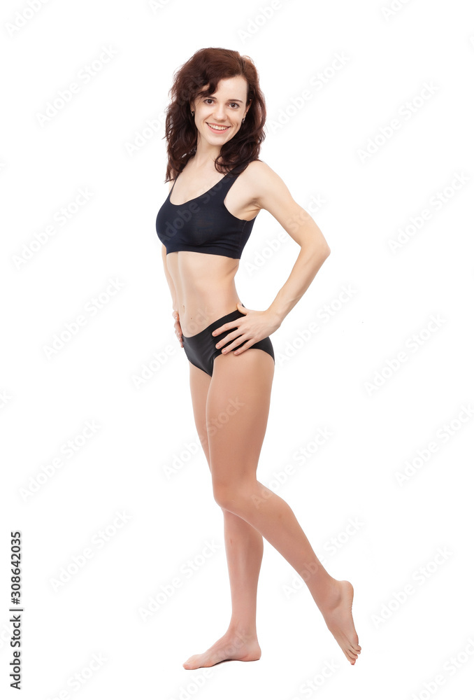 A barefoot girl in a black sports swimsuit is standing on a white background. A barefoot girl in a black sports swimsuit is standing on a white background.