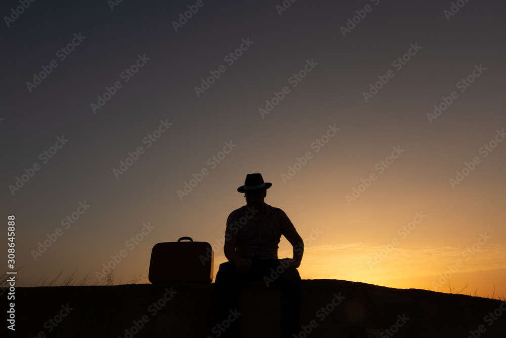 silhouette of man with suitcase at sunrise