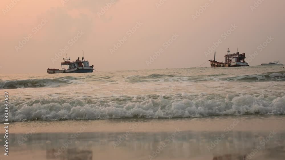The sea is approaching the beach and a fishing boat floats in the sea. The sea is approaching the beach and a fishing boat floats in the sea.