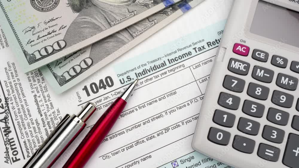 USA Tax Form 1040 and dollar bills, close up. High angle view. USA Tax Form 1040 and dollar bills, close up. High angle view.
