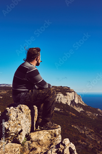 A man sitting on a top of a mountain