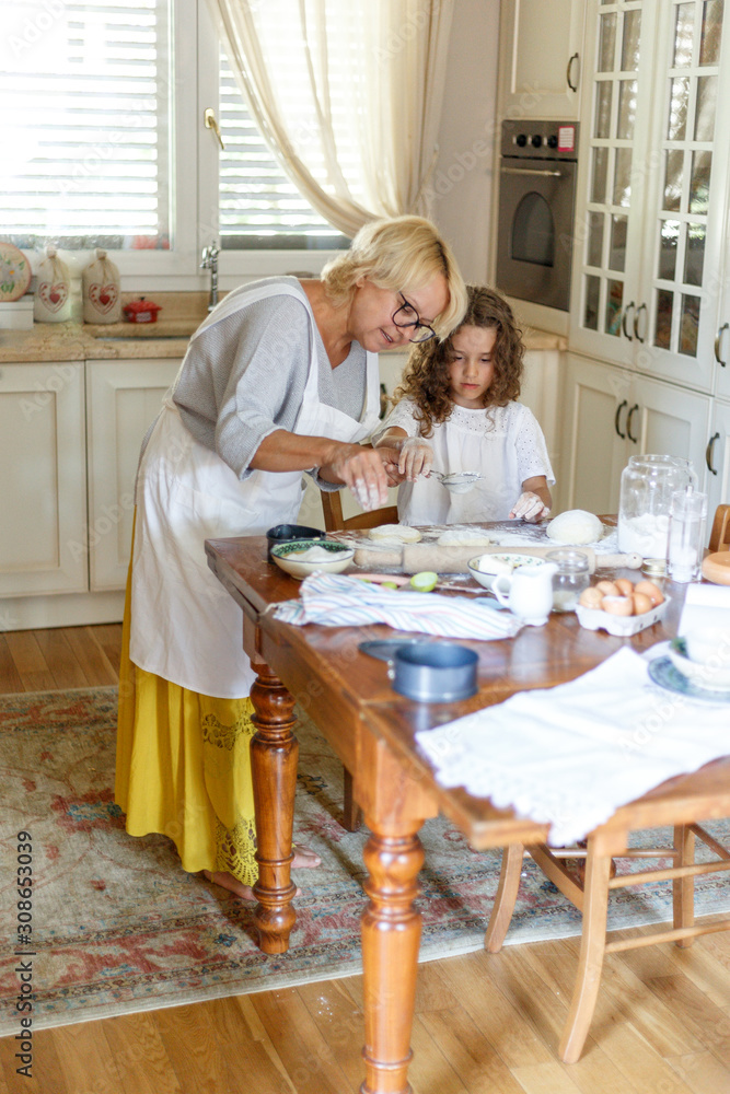 Cute girl and her grandmother cooking in kitchen. Have fun yime together. Vertical view. Cute girl and her grandmother cooking in kitchen. Have fun yime together. Vertical view.
