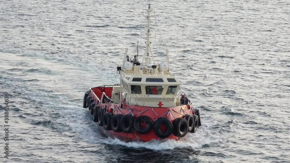 red and white powerful tugboat with tire protected boat sides sails on calm sea water surface to oil tanker Onyx red and white powerful tugboat with tire protected boat sides sails on calm sea water surface to oil tanker Onyx