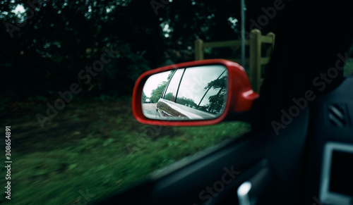 Looking into the side mirror of a car as it drives through the countryside with the view of a car following behind.