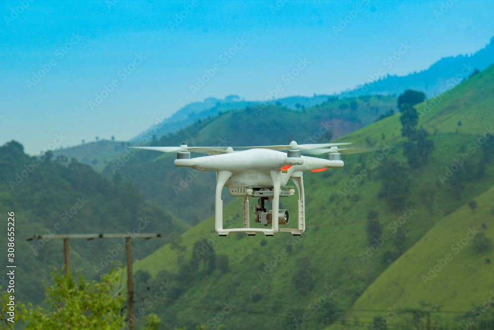 White drone quad copter with high resolution digital camera flying on autumn background. White drone quad copter with high resolution digital camera flying on autumn background.