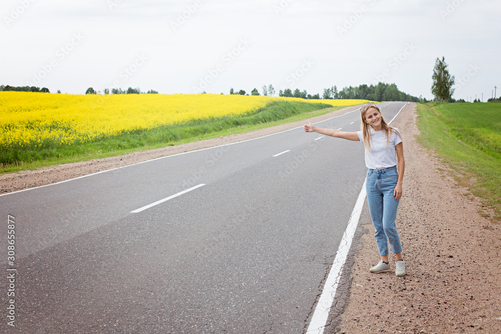 Girl with a smile votes on the road stopping the car