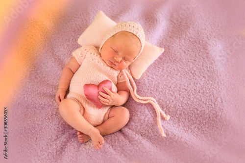 Newborn baby with a symbol of love in her hands. Valentine's Day