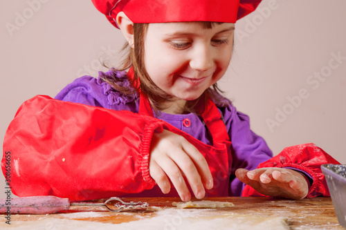 Young little chef girl with cook hat and apron  learn to prepar sweet desert at home kitchen. Nutrition and education concept photo