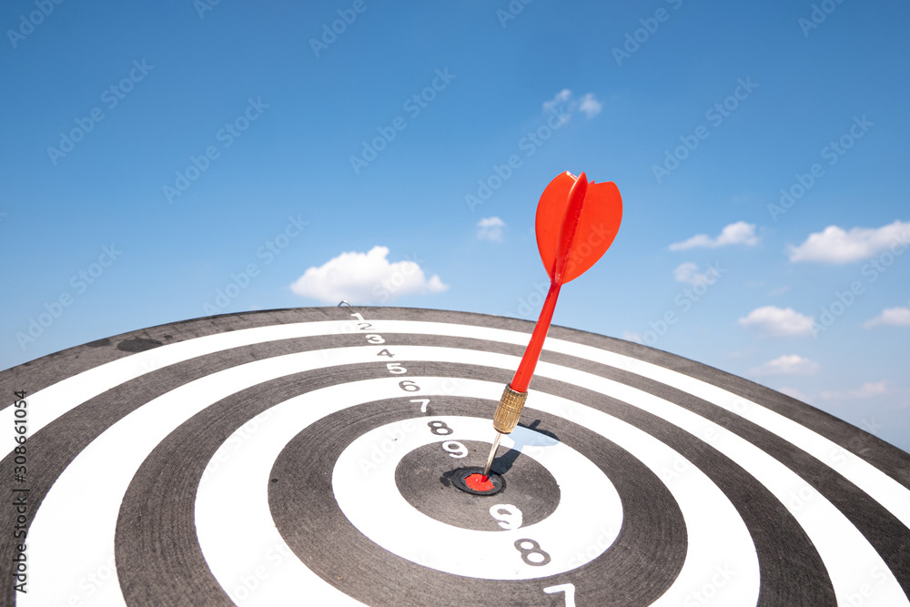Dart arrow hit on bulleyes of dartboard with blue sky, Planning new business target and goals Dart arrow hit on bulleyes of dartboard with blue sky, Planning new business target and goals