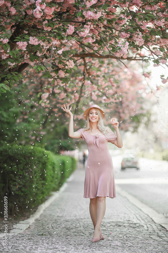 Beautiful girl posing in The Pink peach and Sakura Flowers Blooming Garden. Young attractive woman smiling, posing outdoor. Spring, beauty concept © ElenaBatkova