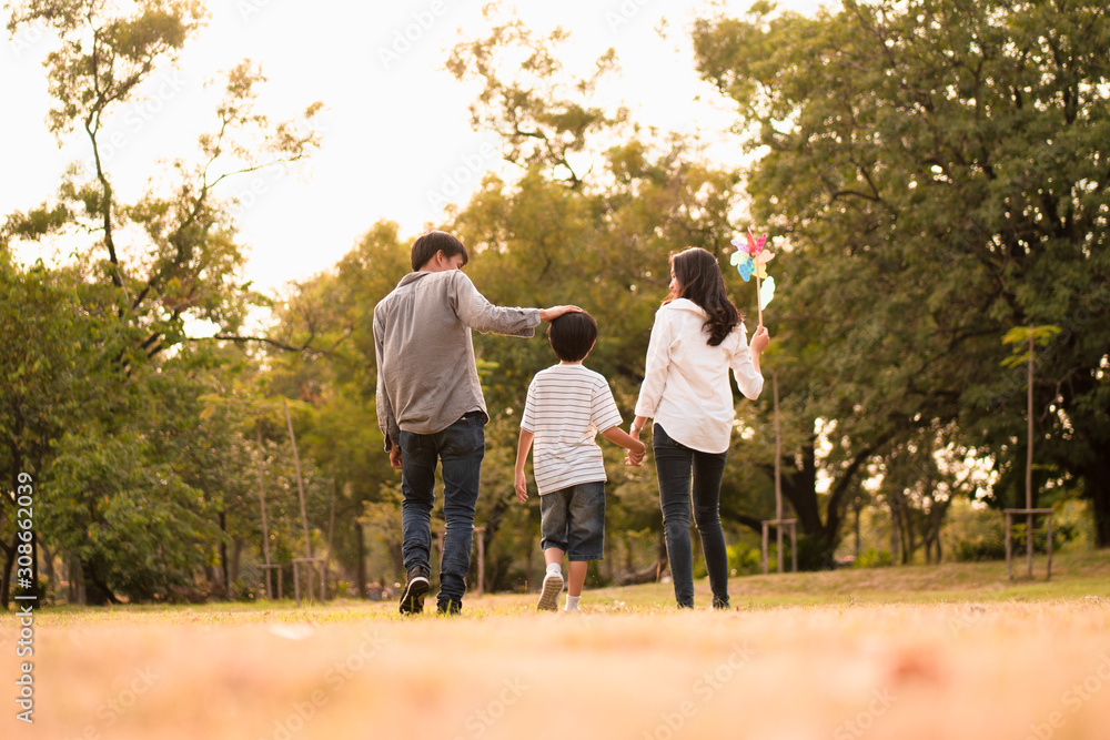 Scene from behind of Asian happy family spend time together walking and relaxing at the park in the afternoon autumn, concept family togetherness, warm hearted family, parenthood, happy family outing. Scene from behind of Asian happy family spend time together walking and relaxing at the park in the afternoon autumn, concept family togetherness, warm hearted family, parenthood, happy family outing.