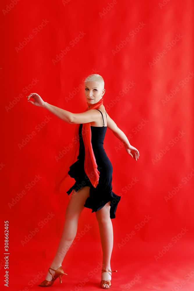 Woman 40 45 years old in a black dress dancing tango on a red background. Woman 40 45 years old in a black dress dancing tango on a red background.