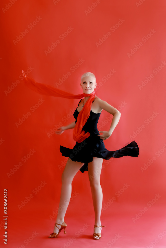 Woman 40 45 years old in a black dress dancing tango on a red background.