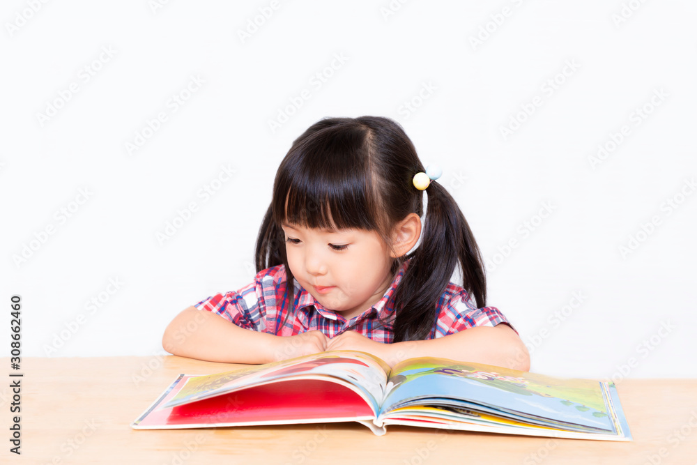 白背景の前で本を読む幼い女の子。幼児、教育、読書、学習、成長、育児イメージ 白背景の前で本を読む幼い女の子。幼児、教育、読書、学習、成長、育児イメージ