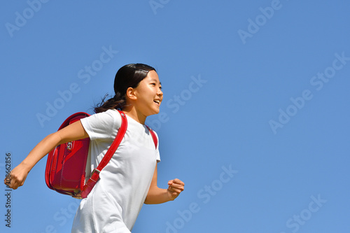 青空で走る小学生の女の子（ランドセル）