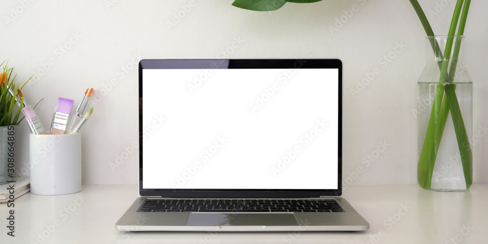 Cropped shot of modern workplace with open blank screen laptop computer and office supplies Cropped shot of modern workplace with open blank screen laptop computer and office supplies