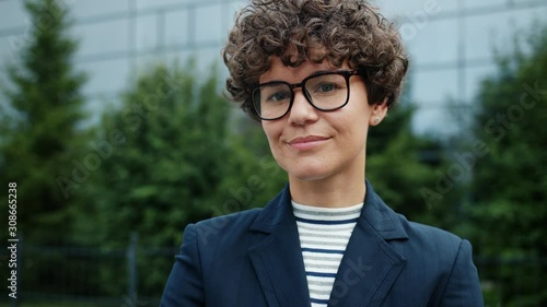 Wallpaper Mural Smiling ambitious girl in suit and glasses standing in city center near office building looking at camera with cheerful face. Confidence and modern people concept. Torontodigital.ca