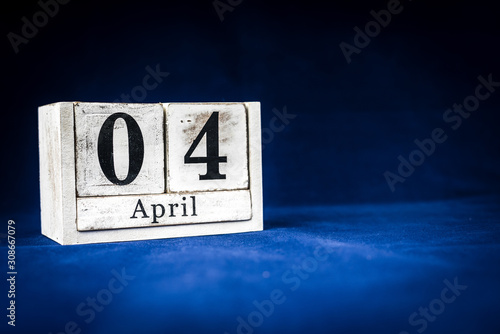 April 4th, Fourth of April, Day 4 of month April - rustic wooden white calendar blocks on dark blue background with empty space for text.