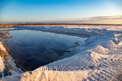 Nature reserve Saline Margherita di Savoia, Apulia, Italy: The salt pan. Salt flats area for sea salt production. A salt marsh, an ecosystem on Adriatic sea. Heaps of salt at sunset ready for harvest photo