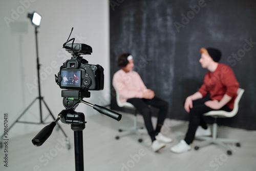 Screen of digital video camera with two vloggers having conversation in studio