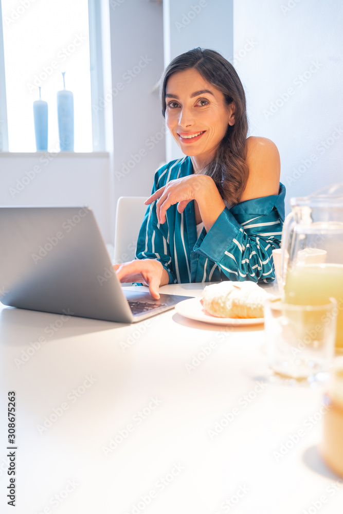 Smiling lady having breakfast and using laptop stock photo Smiling lady having breakfast and using laptop stock photo