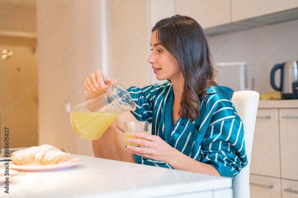 Calm woman pouring juice in the kitchen stock photo Calm woman pouring juice in the kitchen stock photo