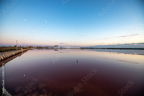 Nature reserve Saline Margherita di Savoia  Apulia  Italy  Salt flats  salt pan area for salt production. colored red waters from the alga Dunaliella salina. Salt and the moon reflected in the marsh