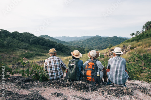 Group of elderly Asian lovers sit and relax on the foothills after they have climbed and adventure to this place. They use their free time after retirement.