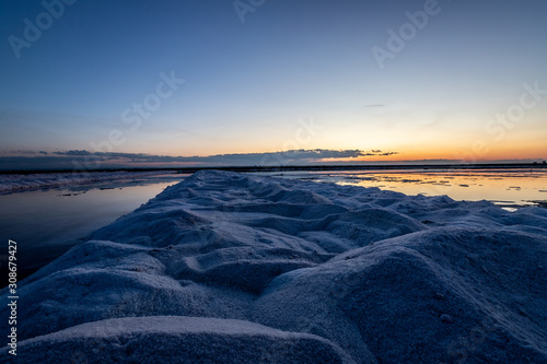 Nature reserve Saline Margherita di Savoia, Apulia, Italy: The salt pan. Salt flats area for sea salt production. A salt marsh, an ecosystem on Adriatic sea. Heaps of salt at sunset ready for harvest photo