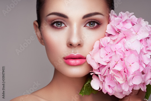 Portrait of beautiful young woman with flowers. Brunette woman with luxury ma...