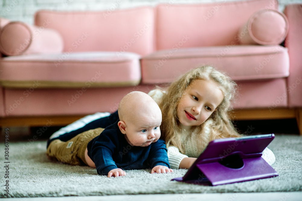 The concept of family love, care and education.Brother and sister are watching cartoon on laptop while lying on floor.friendly enthusiastic smart little children. Children and social addiction The concept of family love, care and education.Brother and sister are watching cartoon on laptop while lying on floor.friendly enthusiastic smart little children. Children and social addiction