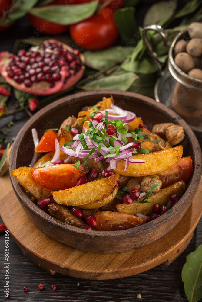 Meat stewed with potato in tomato sauce with pomegranate on wooden table