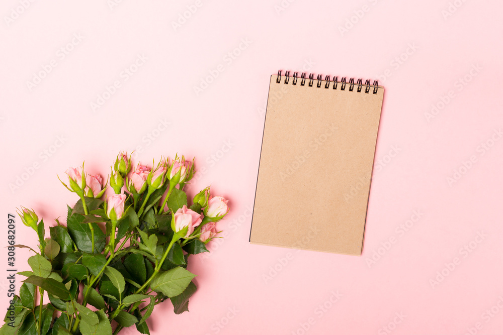 Mock up with pink roses and blank brown craft notebook.Minimalist flat lay, pink background.