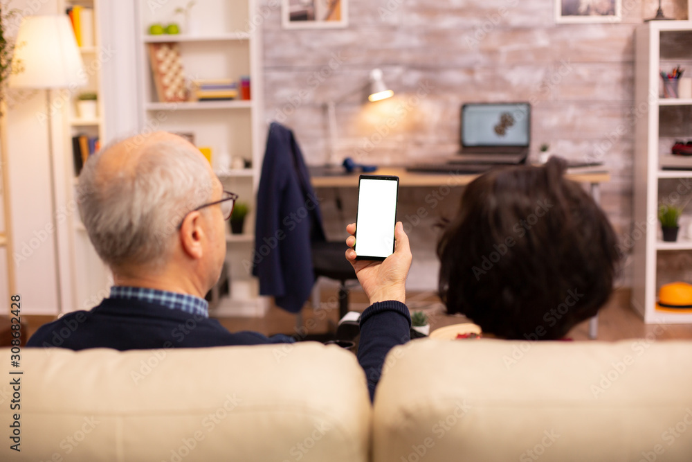 Back view of elderly retired couple looking at a smartphone with white isolated screen Back view of elderly retired couple looking at a smartphone with white isolated screen