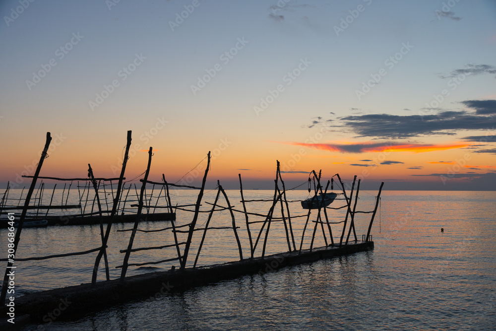 Sunset scene of the small dock of Savudrija with the typical wooden cranes.