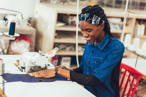 Young african textile worker sewing on production line. photo