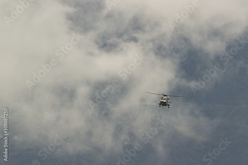 military helicopter flying against the background of mountains and clouds