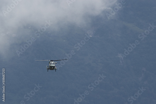 military helicopter flying against the background of mountains and clouds