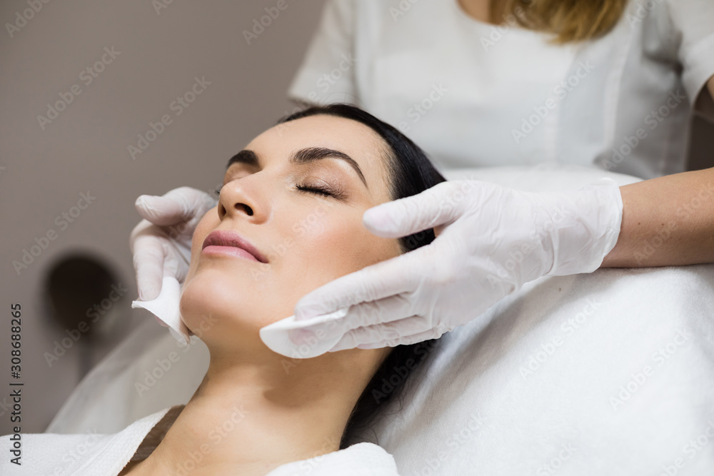 Female beautician cleanses the skin. Cosmetology procedure in the beauty salon. Facial treatment. Beautiful spa woman with perfect fresh clean skin.