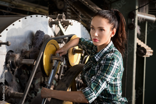 Beautiful brunette girl repairs the spinning machine