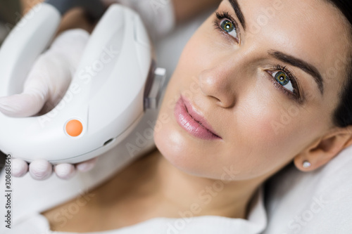 Hardware cosmetology. Skin treatments using photorejuvenation and treatment of benign pigmented lesions. Close-up portrait of a young woman getting laser resurfacing of skin in a cosmetology clinic.
