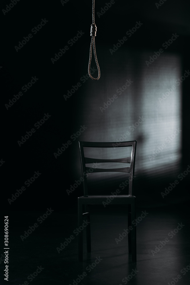 chair under hanging rope noose on black background with lighting, suicide  prevention concept Stock Photo