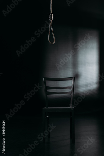 Slika na platnu chair under hanging rope noose on black background with lighting, suicide preven