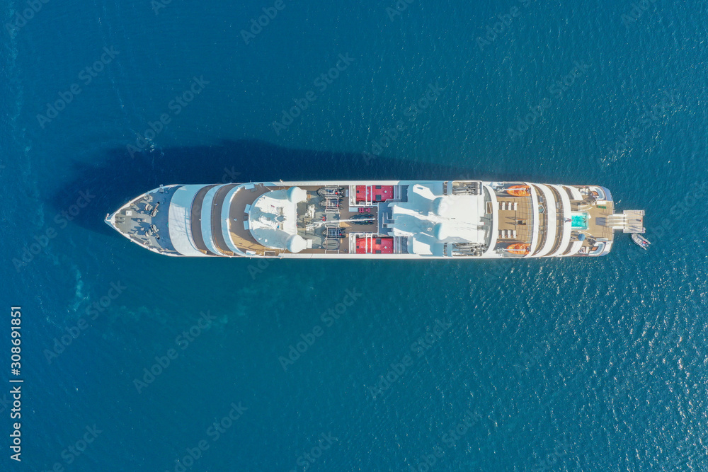 Foto Stock Top down aerial image large holiday cruise ship in the middle of  the ocean with the small speed boat across around. | Adobe Stock