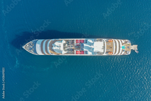 Top down aerial image large holiday cruise ship in the middle of the ocean with the small speed boat across around.